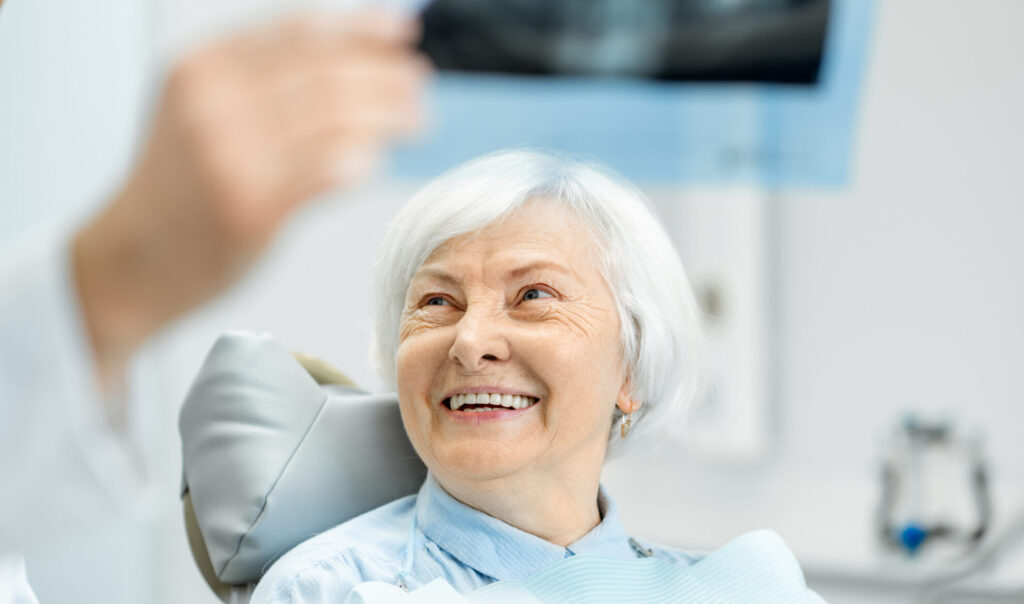 Dentist showing x-ray to the elder woman in the dentall office